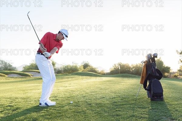 Hispanic man hitting ball on golf course
