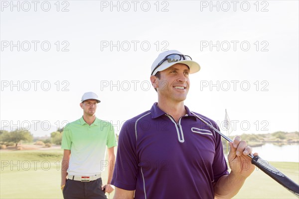 Friends holding golf clubs on golf course