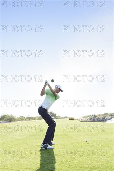 Caucasian man teeing off on golf course