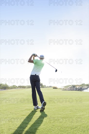 Caucasian man teeing off on golf course