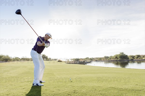 Hispanic man teeing off on golf course