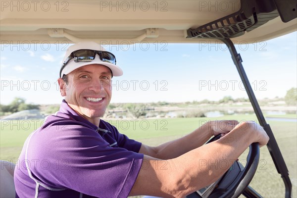 Portrait of smiling Hispanic man driving golf cart