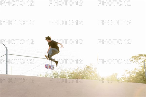 Hispanic man performing mid-air trick on skateboard