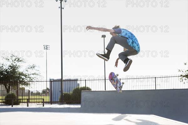 Hispanic man performing mid-air trick on skateboard