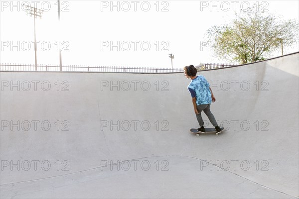 Hispanic man riding skateboard on ramp