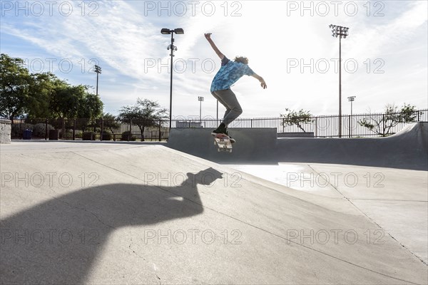 Hispanic man performing mid-air trick on skateboard