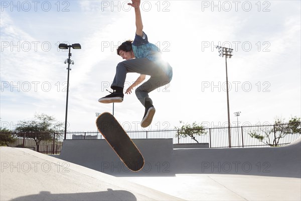 Hispanic man performing mid-air trick on skateboard