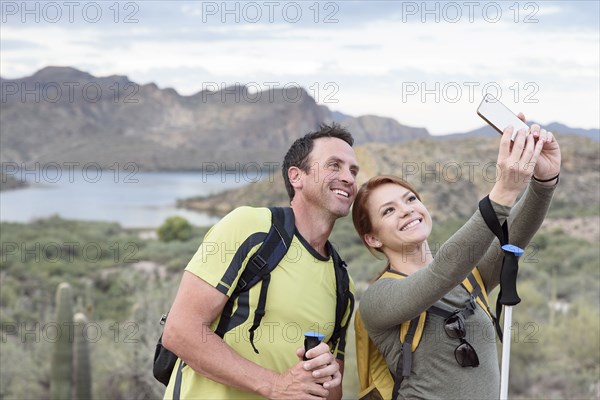 Hikers posing for cell phone selfie in desert