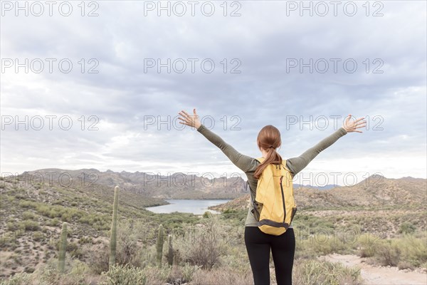 Caucasian hiker standing with arms raised in desert