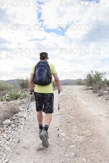 Hispanic man hiking on rocky path in desert