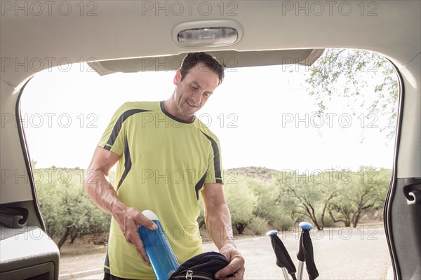 Hispanic man pulling water bottle from backpack in car