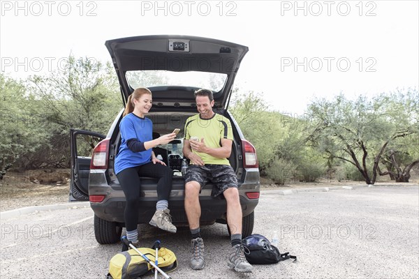 Hikers sitting in car texting on cell phones