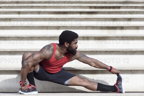 African American man stretching leg on bleachers