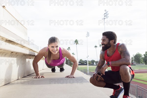 Trainer watching woman do push-ups on bleachers