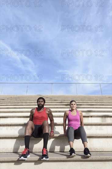 Man and woman doing triceps dips on bleachers