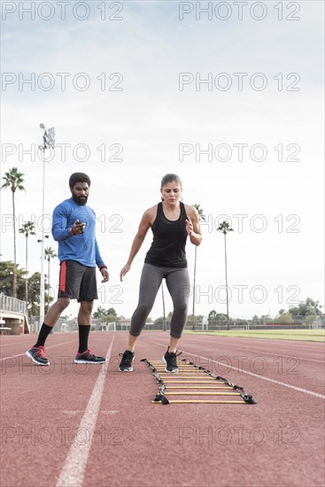 Trainer watching woman running ladder