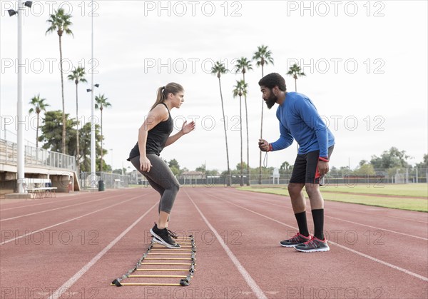 Trainer watching woman running ladder