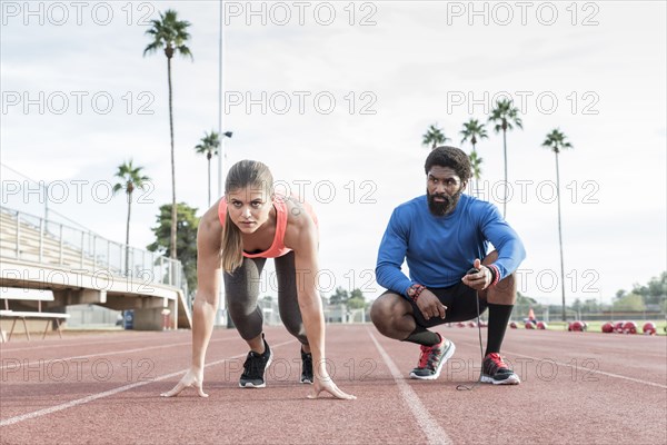 Man timing woman on track in starting position