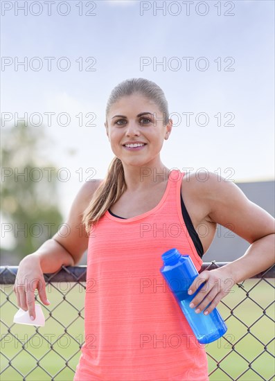 Hispanic woman leaning on fence