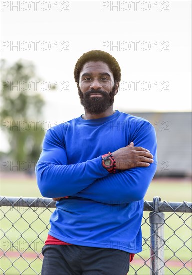 African American man leaning on fence