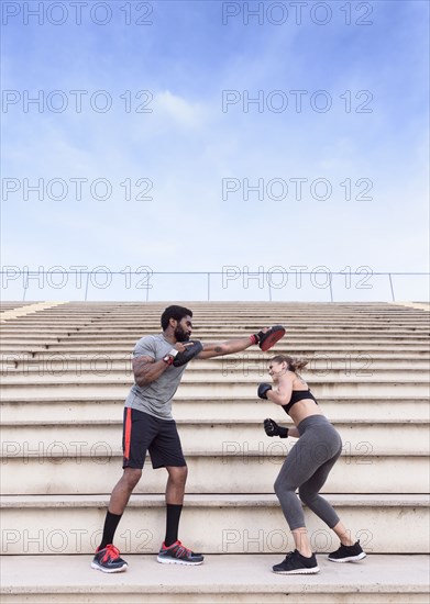 Trainer and woman boxing on bleachers