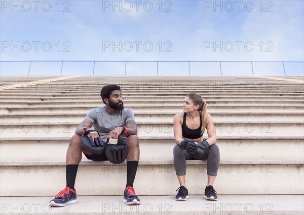 Trainer and woman resting on bleachers