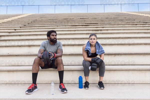 Trainer and woman resting on bleachers