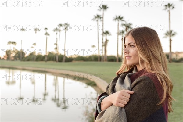 Pensive Hispanic woman near lake