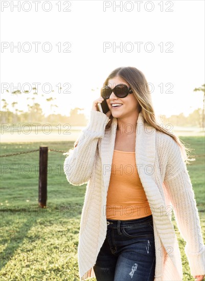 Smiling Hispanic woman wearing sunglasses talking on cell phone