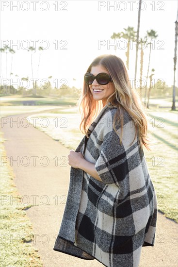 Smiling Hispanic woman wearing plaid poncho on path