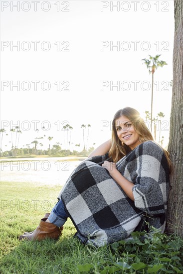 Hispanic woman leaning on tree