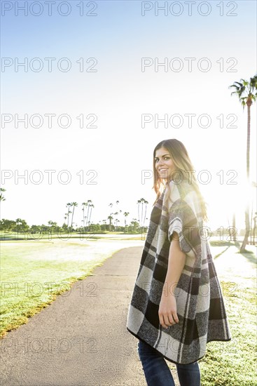 Hispanic woman wearing poncho walking on path