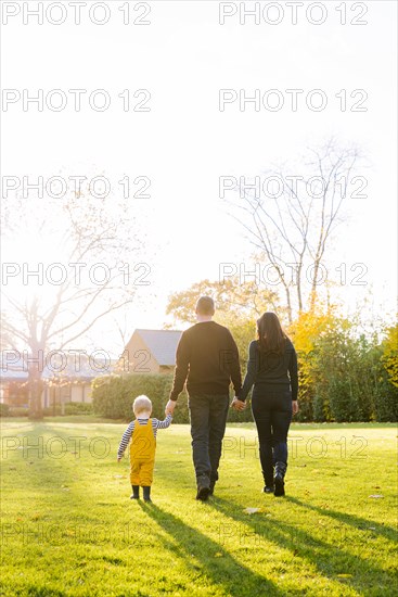 Caucasian mother and father walking in field with son