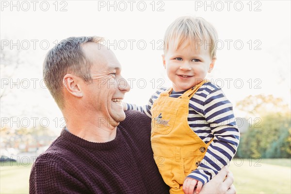 Laughing Caucasian father holding son