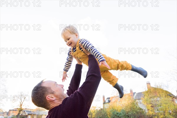 Caucasian father lifting son