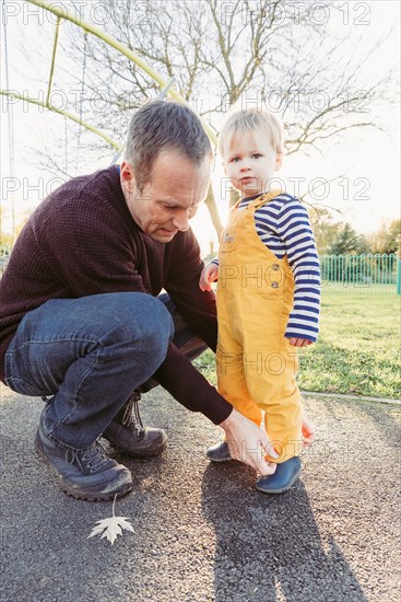 Caucasian father adjusting pants for son