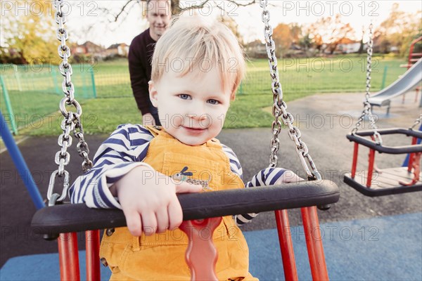 Caucasian father pushing son on swing