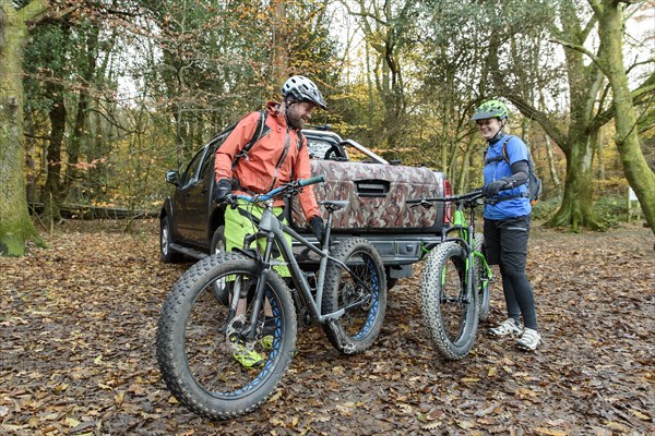 Caucasian couple holding bicycles near pickup truck