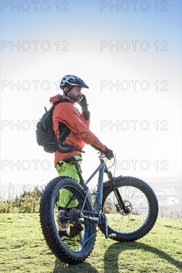 Caucasian man holding bicycle talking on cell phone