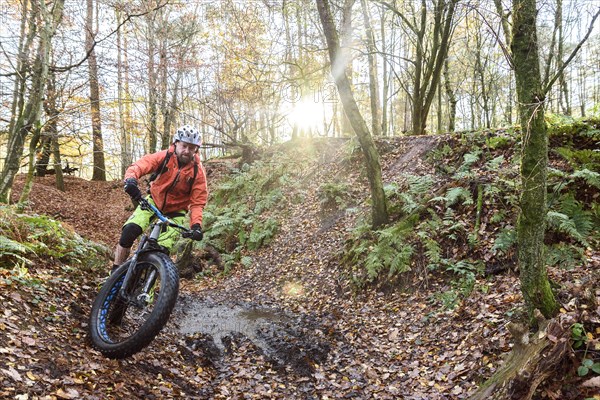 Caucasian man steering bicycle around mud puddle