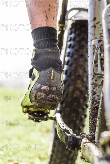 Leg of Caucasian man splattered in mud riding bicycle