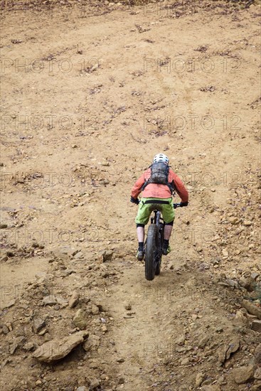 Caucasian man descending dirt trail on bicycle