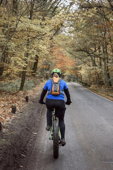 Caucasian woman riding bicycle on forest road