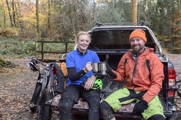 Caucasian couple toasting with coffee cups in pickup truck