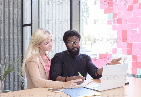 Creative business people using laptop at table