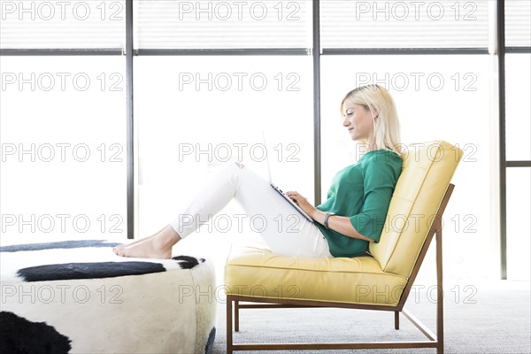 Caucasian woman sitting in chair using laptop