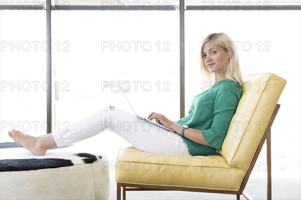 Caucasian woman sitting in chair using laptop