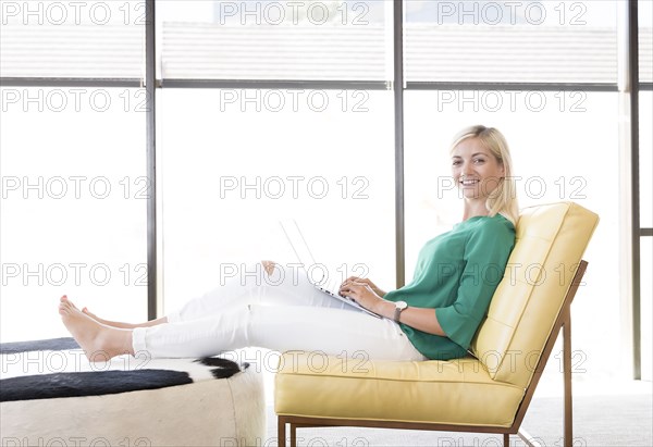 Caucasian woman sitting in chair using laptop