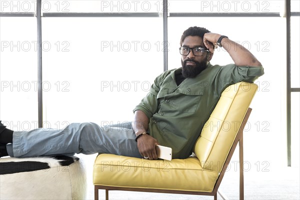 Black man sitting in chair holding cell phone