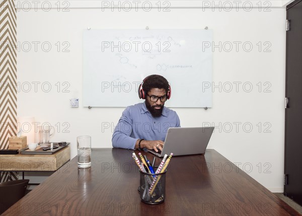 Black businessman wearing headphones using laptop